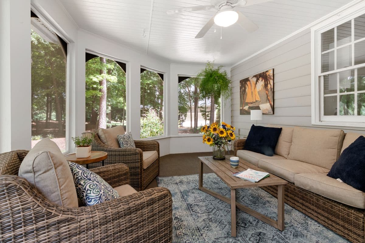 A sunroom with wicker seating and fresh flowers